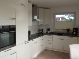 eine weiße Küche mit weißen Schränken und einem Fenster in der Unterkunft Auszeit am Fähranleger in Grünendeich