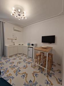 a kitchen with a table and a television in a room at Solis Domus Oriens in Ostuni