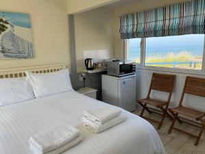 a bedroom with a bed with two chairs and a window at Poachers Pocket Seaview in Bacton
