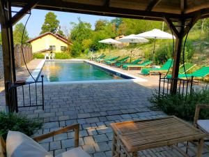 a swimming pool with green chairs and umbrellas at Cascina Ghitin Relais in Asti