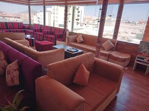 a waiting room with couches and tables and windows at Petra Cabin Inn Hostel&Resturant in Wadi Musa