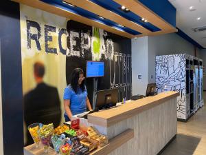a woman standing at the reception desk of a restaurant at ibis budget Itaperuna in Itaperuna