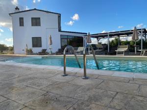 a swimming pool with umbrellas in front of a house at Agriturismo Masseria Saittole in Carpignano Salentino