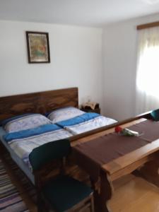 two beds in a room with a table and a chair at Kuća za odmor Lešnica in Brod na Kupi