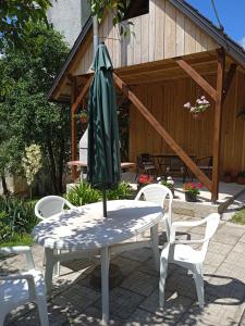 - une table avec un parasol vert assise sur une terrasse dans l'établissement Kuća za odmor Lešnica, à Brod na Kupi