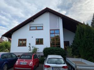 ein weißes Haus mit davor geparkt in der Unterkunft Ferienwohnung Geiger in Sersheim