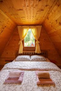 Bett in einer Holzhütte mit Fenster in der Unterkunft Lodge Drveni Kutak in Sekulić 