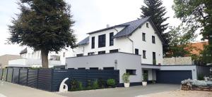 een wit huis met een zwart hek ervoor bij moderne Neubau-Wohnung mit Kamin und 35qm Dachterrasse in Trossingen
