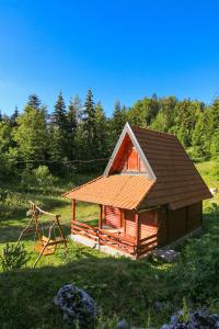 eine kleine Hütte mit einem Dach und einer Schaukel in der Unterkunft Lodge Drveni Kutak in Sekulić 