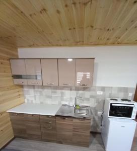 La cuisine est équipée de placards blancs, d'un évier et d'une cuisinière. dans l'établissement Guest House RG, à Žabljak