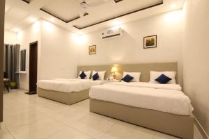 two beds in a hotel room with white walls at Cuzzy Inn Hotel in Lahore