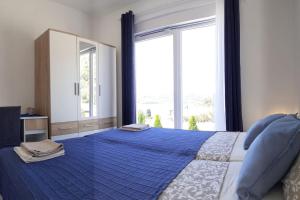 a bedroom with a blue bed with a large window at Vis - luxury holiday villa with swimming pool in Vis