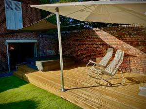 dwa krzesła i parasol na drewnianym tarasie w obiekcie Le Garden & SPA w mieście Compiègne