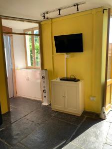 a room with a yellow wall with a flat screen tv at Apartment Casa Dono Il lago in Pognana Lario
