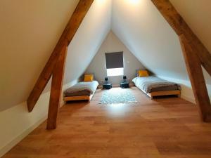 a attic room with two beds and a ceiling with beams at Le domaine des biches in Longueville