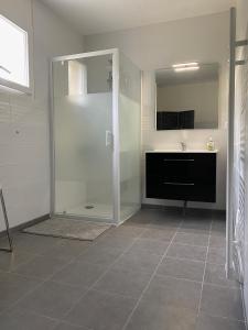 W łazience znajduje się szklana kabina prysznicowa i umywalka. w obiekcie Maison au cœur de la nature w mieście Cerisy-la-Forêt