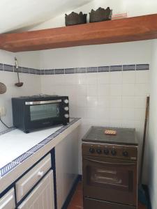 a kitchen with a stove and a microwave on a counter at Sondela Self Catering in São Martinho do Porto