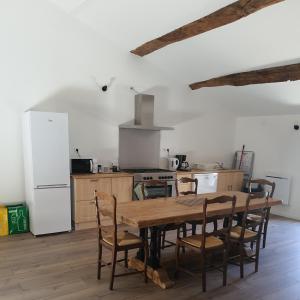 cocina con mesa, sillas y nevera en Gîte Manapany, en Fains-les-Sources