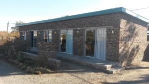 a small brick building with a porch and a door at Onze Rust Guest House and caravanpark in Colesberg