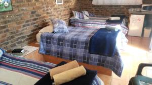 a room with three beds and a brick wall at Onze Rust Guest House and caravanpark in Colesberg