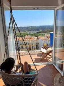 a child sitting in a hanging chair on a balcony at Beach House - Casa de Férias MONTE CLÉRIGO in Aljezur