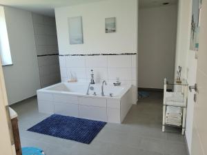 een witte badkamer met een bad en een blauw tapijt bij Ferienwohnung Annashome in Maxhütte-Haidhof