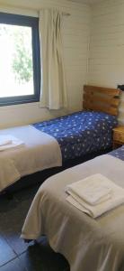 um quarto com 2 camas e uma janela em ALOJAMIENTO PATAGONICO Cabaña Correntoso la hualas em Villa La Angostura