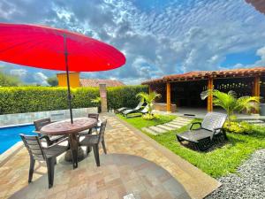 patio con tavolo, sedie e ombrellone rosso di Villa Lupalú - Fincas Panaca- a El Laurel