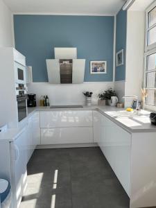 a white kitchen with blue walls and white cabinets at Alte Schule Seinsfeld 