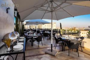 a restaurant with tables and chairs and an umbrella at Retaj Hotel in Amman