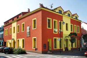 un bâtiment rouge et jaune sur le côté d'une rue dans l'établissement Rezidence Mandragora, à Pardubice