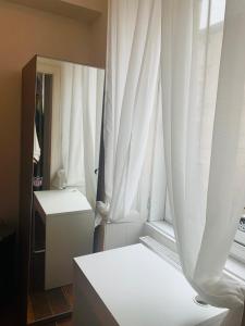 エディンバラにあるDrumdryan Apartment Edinburghの白いカーテン付きの窓が備わる客室です。