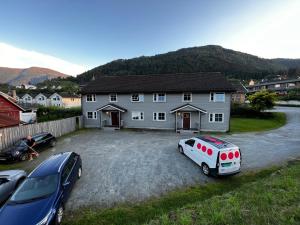 a house with two cars parked in a gravel driveway at Privat rom i leilighet in Sogndal