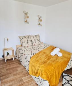 a bedroom with a bed with a yellow blanket at Le Petit Charmeur, parking, Wifi, gare in Flers