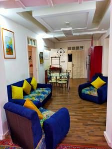 una sala de estar con sofás azules y almohadas amarillas. en Casa Tligui en Asilah