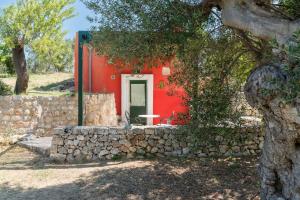 a red house with a stone wall in front of it at Masseria Ottavianello Doc Ostuni in Ostuni