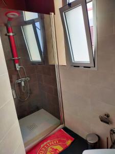 y baño con ducha, 2 ventanas y alfombra roja. en Casa Tligui en Asilah