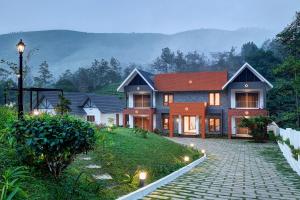 a house with a cobblestone driveway in front at Pakoid Cottages in Idukki