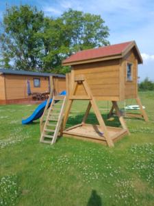 a wooden play house with a ladder and a slide at Domek u Ani in Giżycko