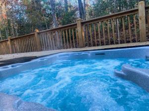 a hot tub in a backyard with a wooden fence at Hibernation Hideaway in Blairsville