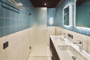 a bathroom with two sinks and a shower at Hotel Babylon Heerhugowaard - Alkmaar in Heerhugowaard