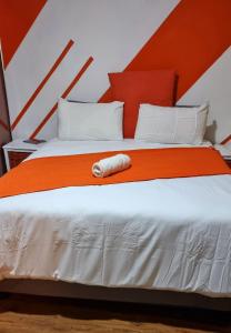 a bed with an orange and white comforter at Epic Den Lodge in Phuthaditjhaba