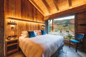 um quarto com uma cama e uma grande janela em Park Chalet Village em Livigno