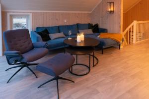 a living room with a blue couch and a table at Lofoten Waterfront luxury lodge in Ballstad