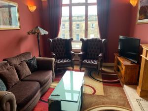 uma sala de estar com um sofá e cadeiras e uma televisão em Your Art Deco Suite em Edinburgo