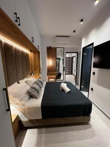 ロードス・タウンにあるCity Compass Luxury Suitesのベッドルーム1室(大型ベッド1台、木製ヘッドボード付)