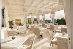 a restaurant with white tables and chairs and windows at Tenuta Del Poggio Antico in Ischia