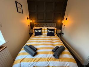 a bedroom with a yellow and white striped bed with black pillows at Modern three bedroom home, Hoyland, Barnsley in Hoyland Nether