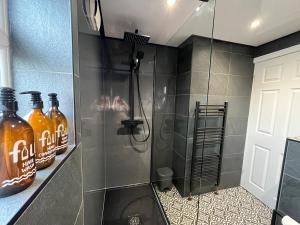a bathroom with a shower with bottles of orange soda at Modern three bedroom home, Hoyland, Barnsley in Hoyland Nether