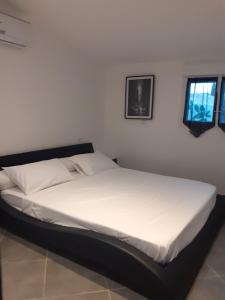 uma cama branca num quarto com uma janela em Villa Piscine em Montady